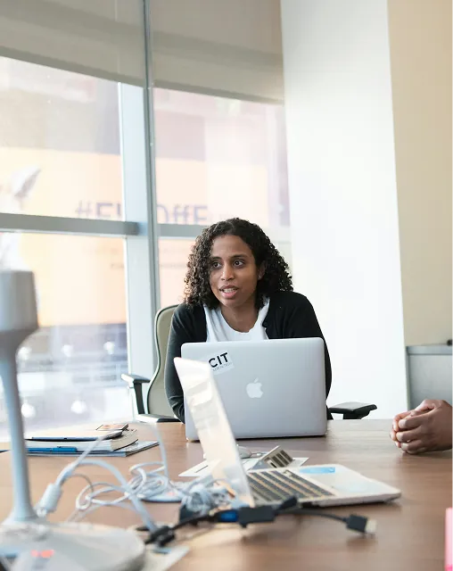 Three colleagues talking at a table in a bright office